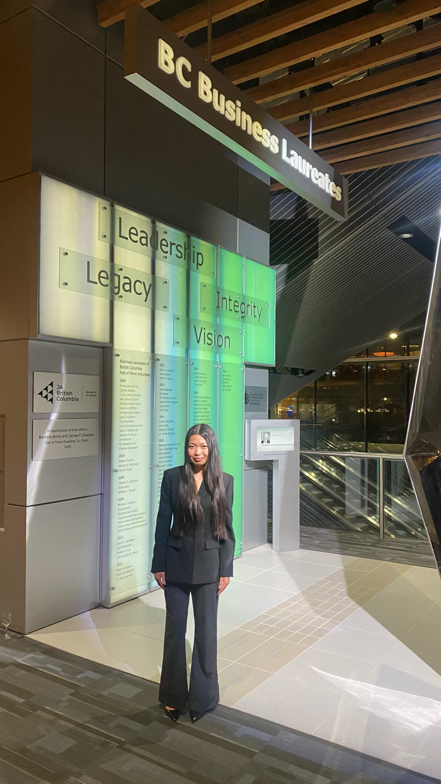 In front of the Leadership, Legacy, Integrity, Vision wall